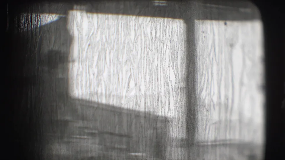 A brief abstracted frame of the circus tent interior, with bright canvas, shadows, and film texture dominating the view.