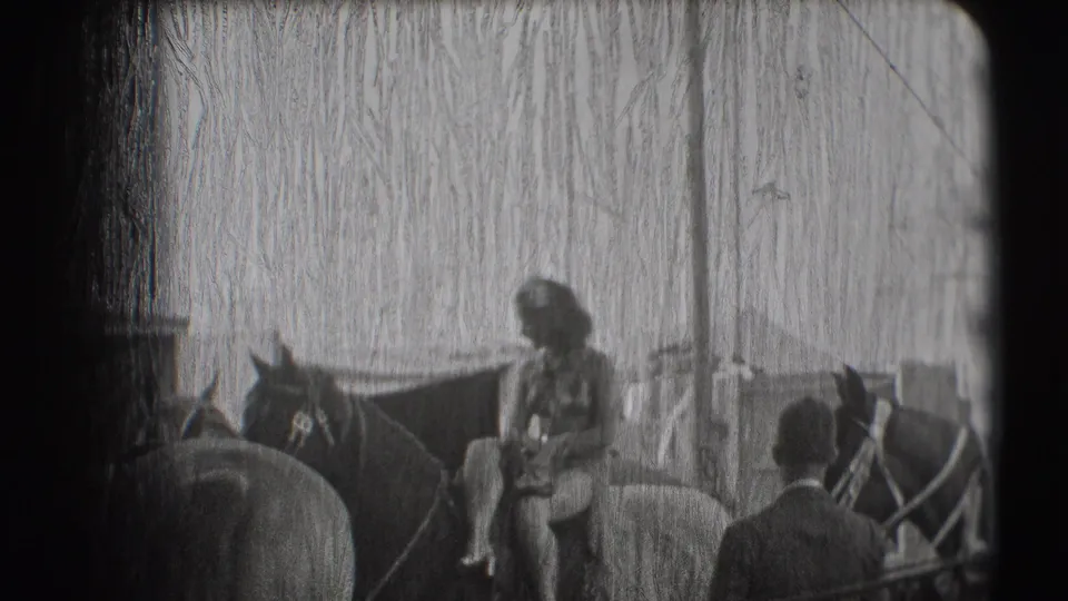 Inside the Sarasota circus tent, a rider sits on horseback while another horse and a standing man are visible nearby.