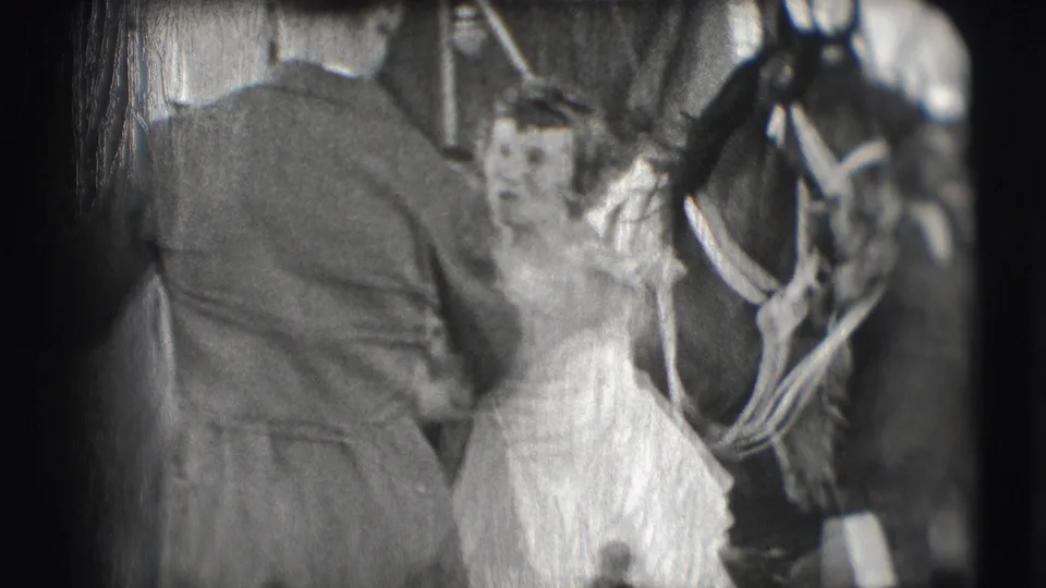 In the Sarasota circus footage, the woman stands beside the bridled horse as a man in a hat faces her in the ring.
