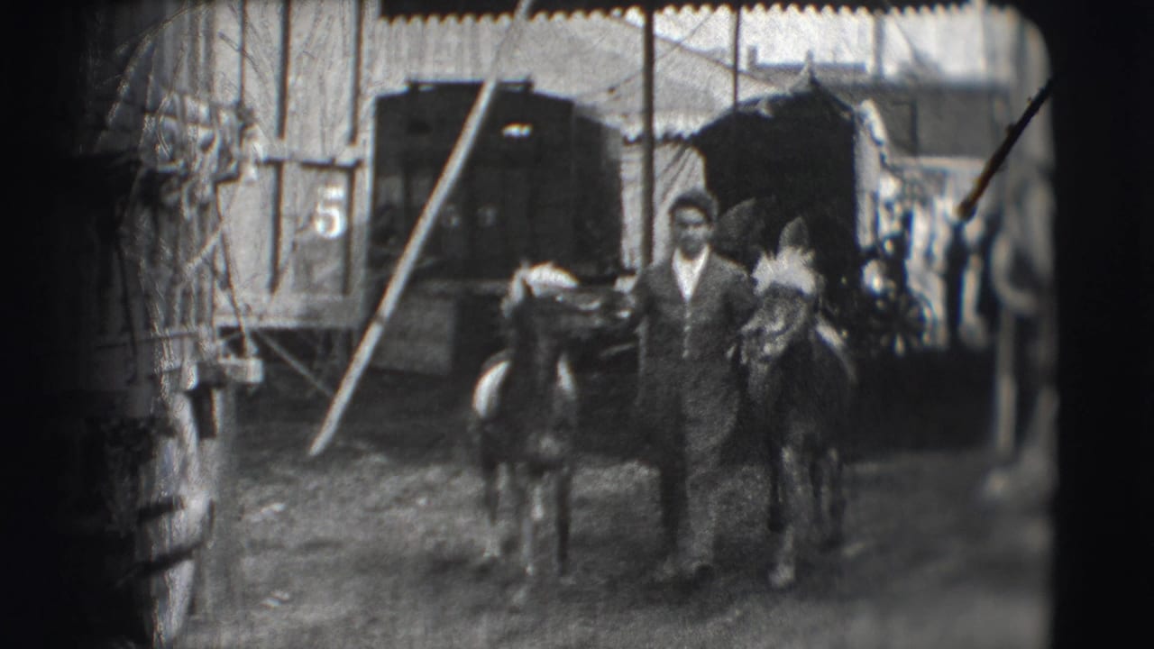 Man walking between two small horses near a wagon and tent opening.