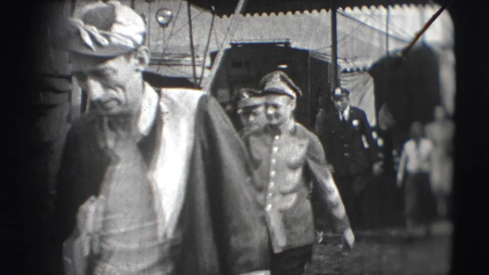 A close view shows an older man in a cap passing the camera, with a uniformed circus worker behind him in the 1948 Sarasota footage.