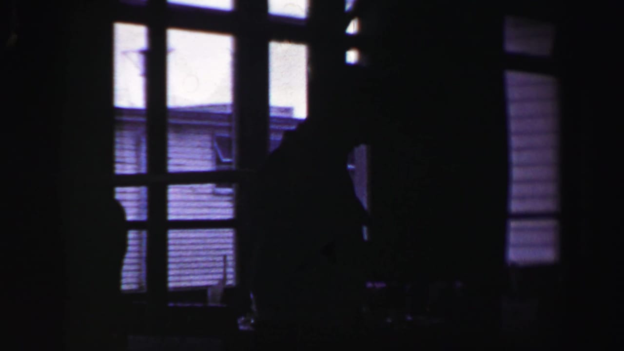 Dark interior view with window panes and a silhouetted person near the right side.