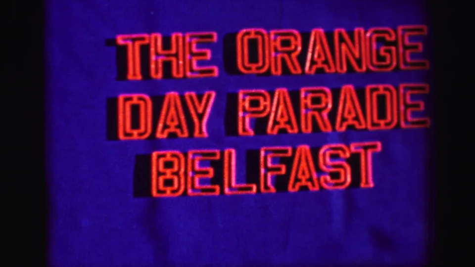 1952 home-movie title card for The Orange Day Parade Belfast, shown in red outlined text on a deep blue background.
