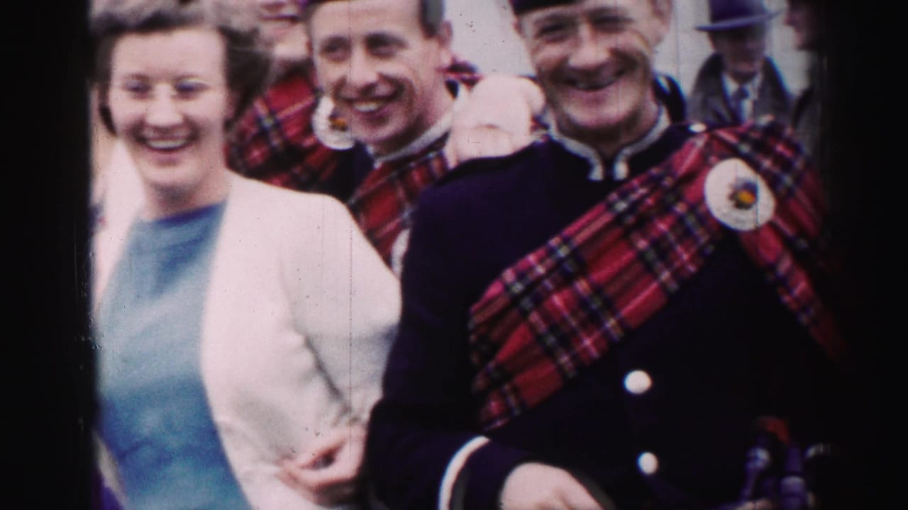 A woman in a pale cardigan stands beside smiling men wearing tartan and formal jackets.