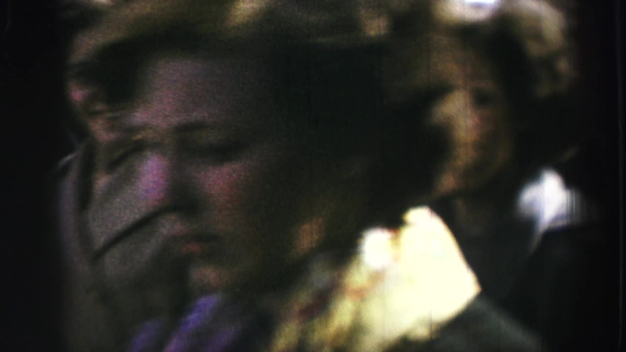 Close, soft-focus view of adults in a crowded outdoor gathering.
