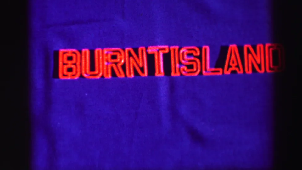1952 8mm frame with red Burntisland title lettering on a purple-blue background, framed by dark film edges.