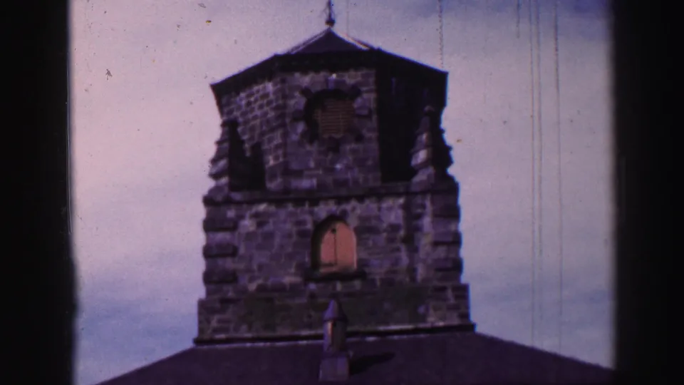 1952 Burntisland frame showing a stone church tower with arched openings, dark roof cap, and visible 8mm wear marks.