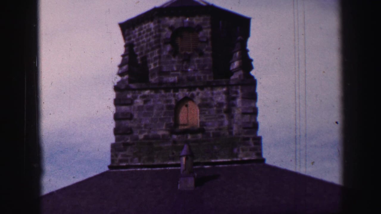 Stone tower above a dark roof, seen through black 8mm frame edges.