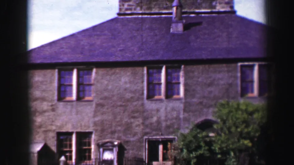 Final frame shows the lower facade, doorway, windows, shrubs, and roof beneath the cropped stone tower.