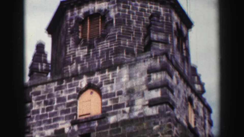1952 United Kingdom 8mm frame of the stone tower, including an arched shutter, louvered opening and stepped architectural detail.