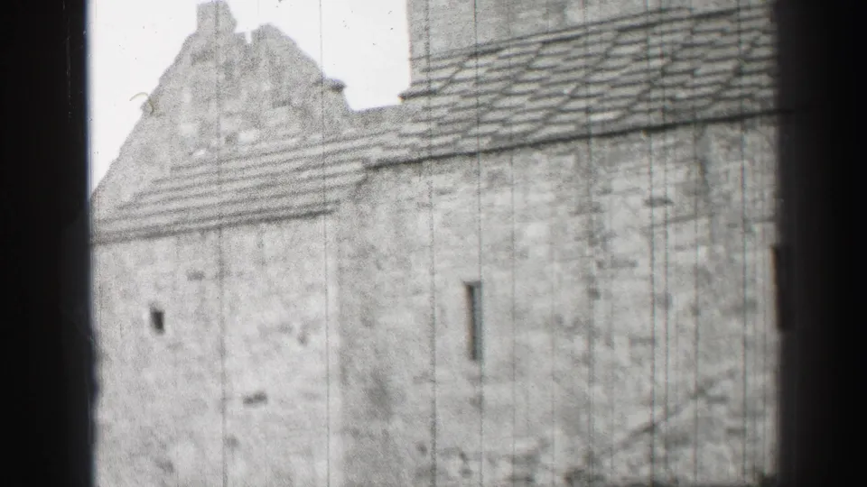 1952 United Kingdom home-movie frame showing a closer architectural view of stonework, roof tiles, and a ruined gable.