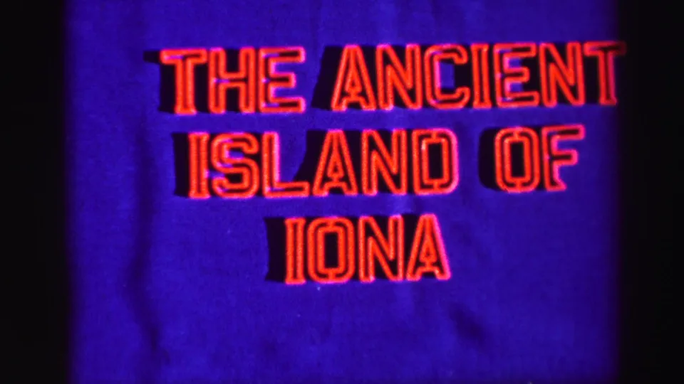 8mm title frame for Iona, with red lettering centered on a blue background and visible film texture.
