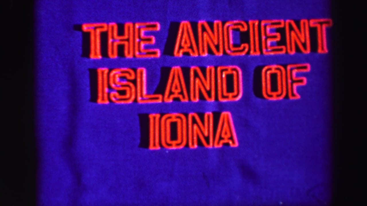 1950s 8mm title card with red neon-style lettering reading The Ancient Island of Iona against a deep blue background.