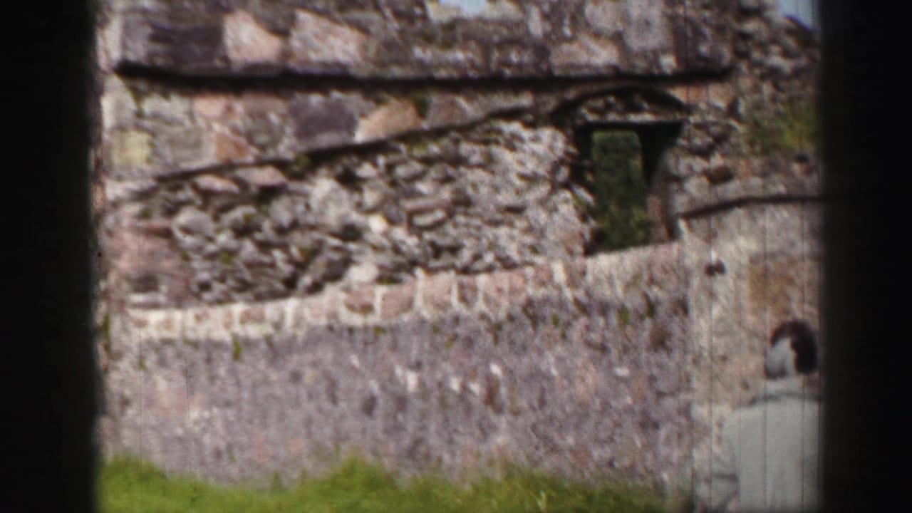 Weathered stonework and a small doorway appear as a visitor stands partly visible from behind in the United Kingdom ruins.