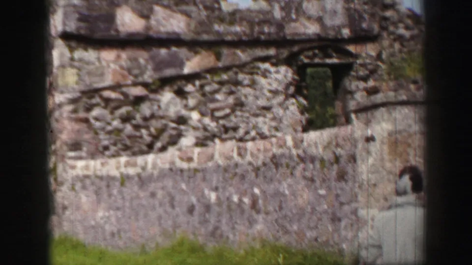 Weathered stonework and a small doorway appear as a visitor stands partly visible from behind in the United Kingdom ruins.
