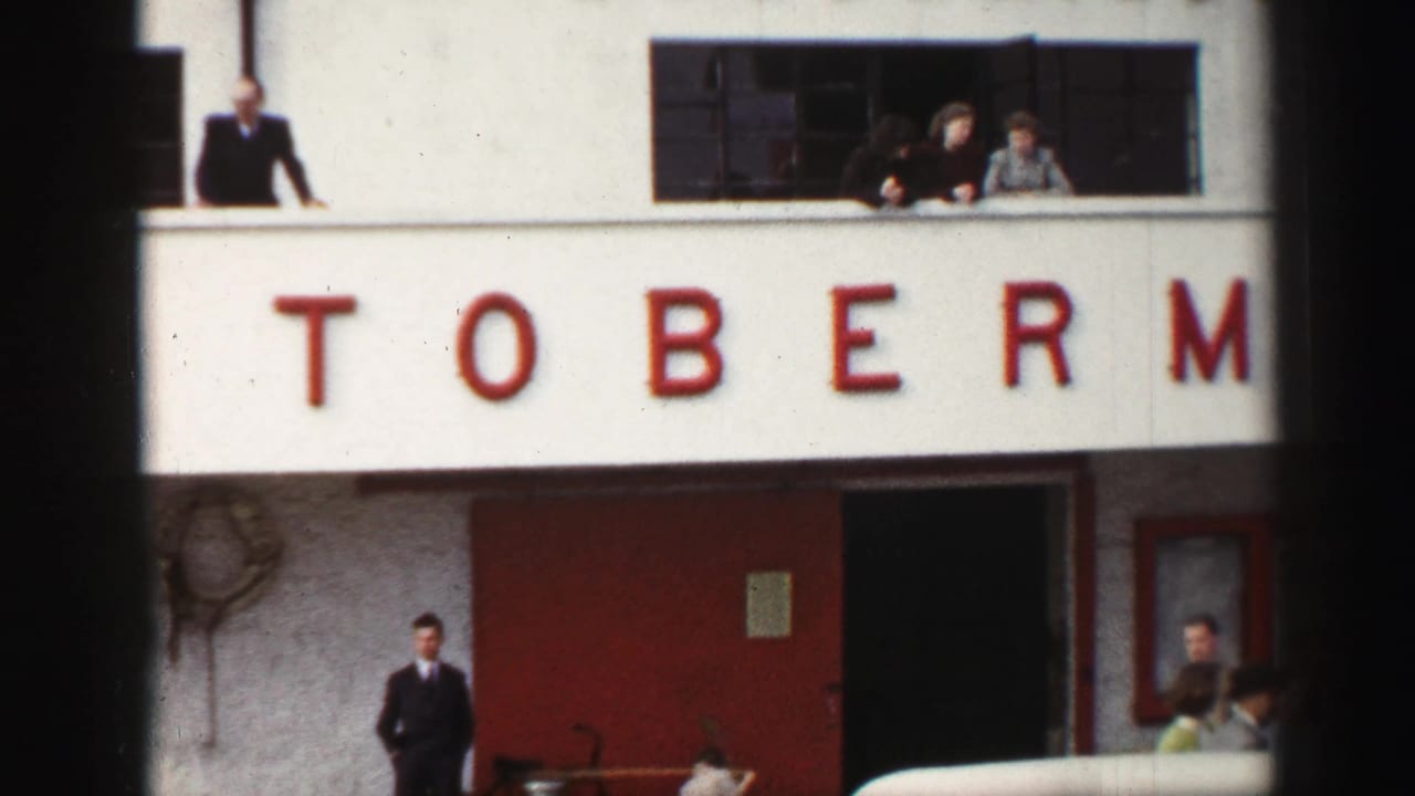 A building facade displays large red TOBERM lettering, with several people watching from upper windows and others standing near the entrance below.