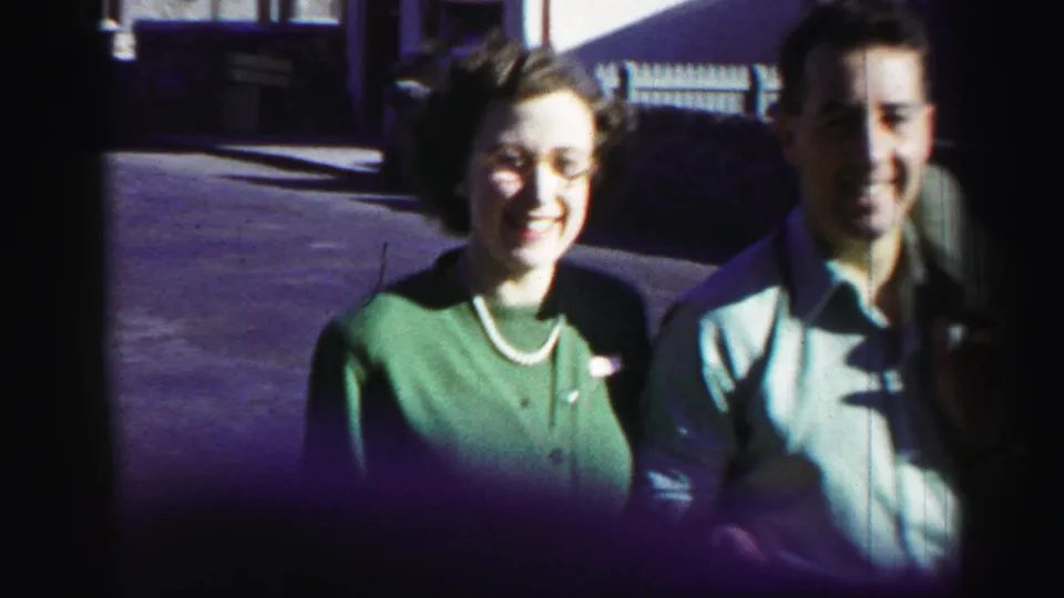 In 1952 United Kingdom home-movie footage, an older woman in green and a smiling man stand close together on a sunny promenade.