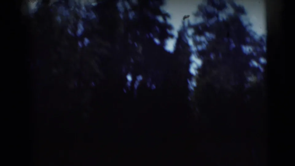 1953 Baraboo, Wisconsin 8mm frame showing dark tree reflections and blue water with heavy shadow at the edges.