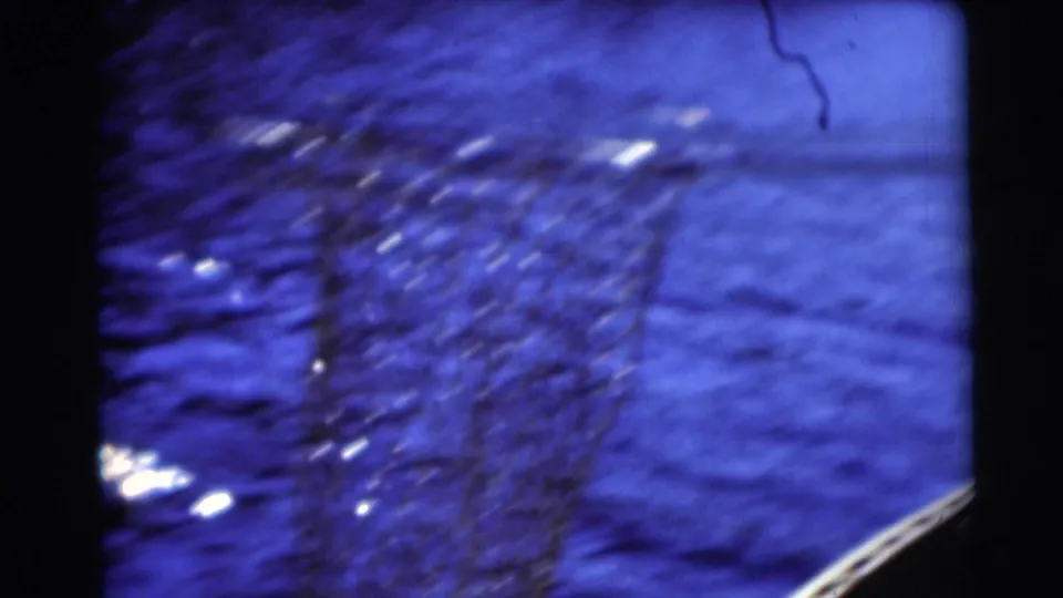 A net or mesh appears in blue rippling water, with highlights and a curved pale edge near the lower right.