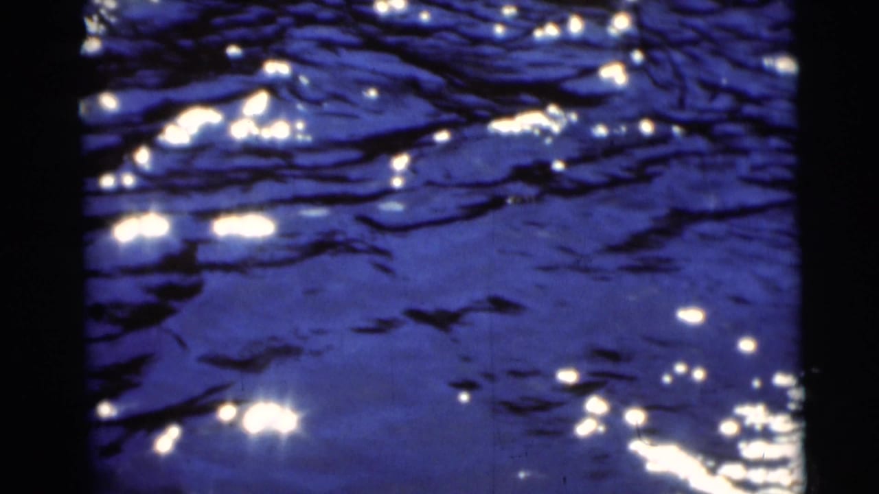 1953 8mm frame from Baraboo, Wisconsin showing dark blue rippling water with scattered bright reflections.
