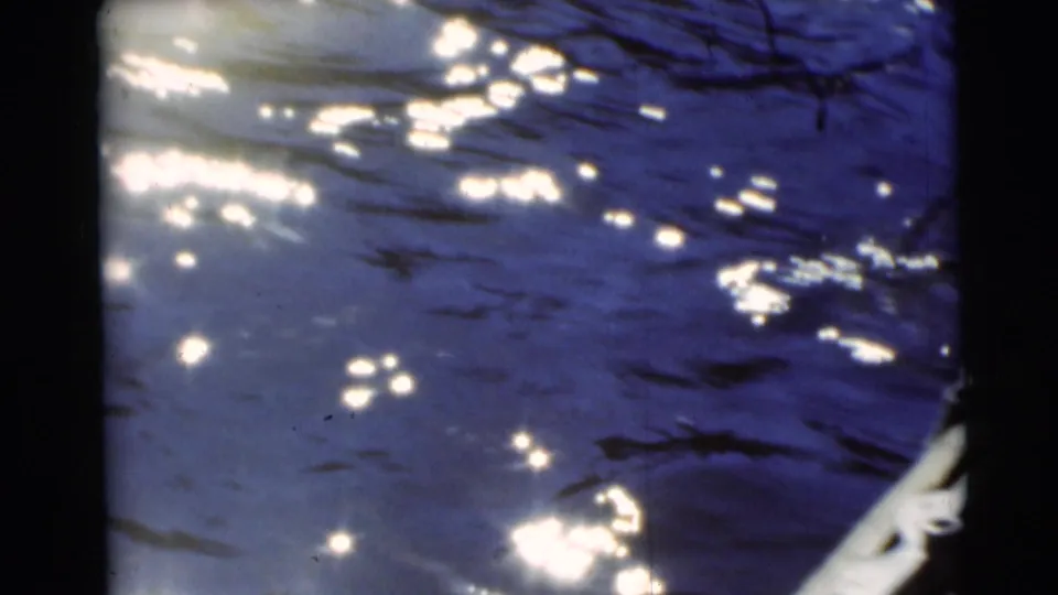 1953 Baraboo 8mm frame with shimmering water and a pale boat or dock edge entering along the right side.