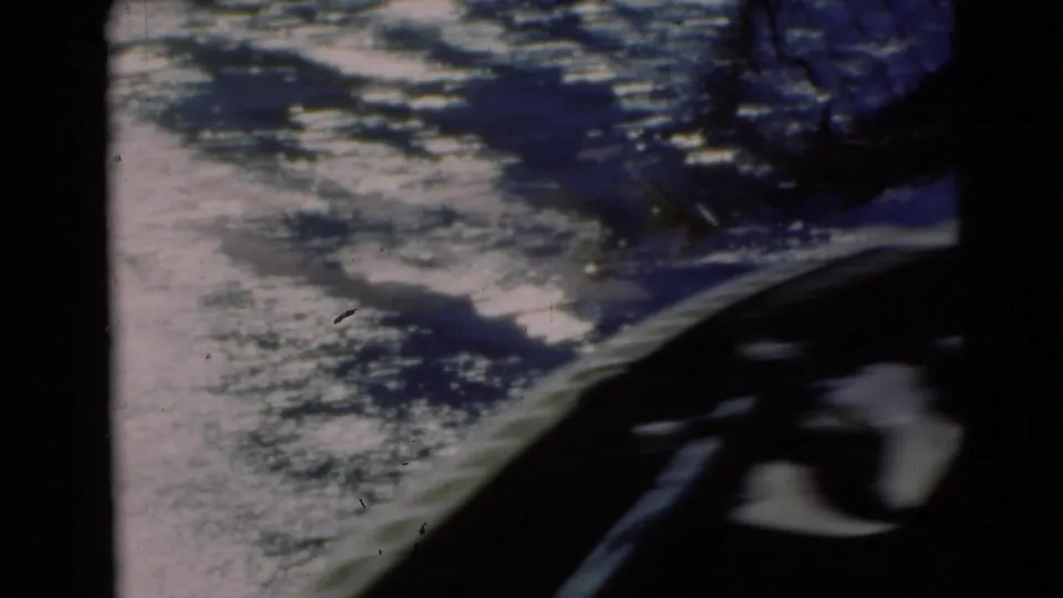 A dark boat edge crosses the lower frame over rippled river water in this 1953 Baraboo home-movie shot.