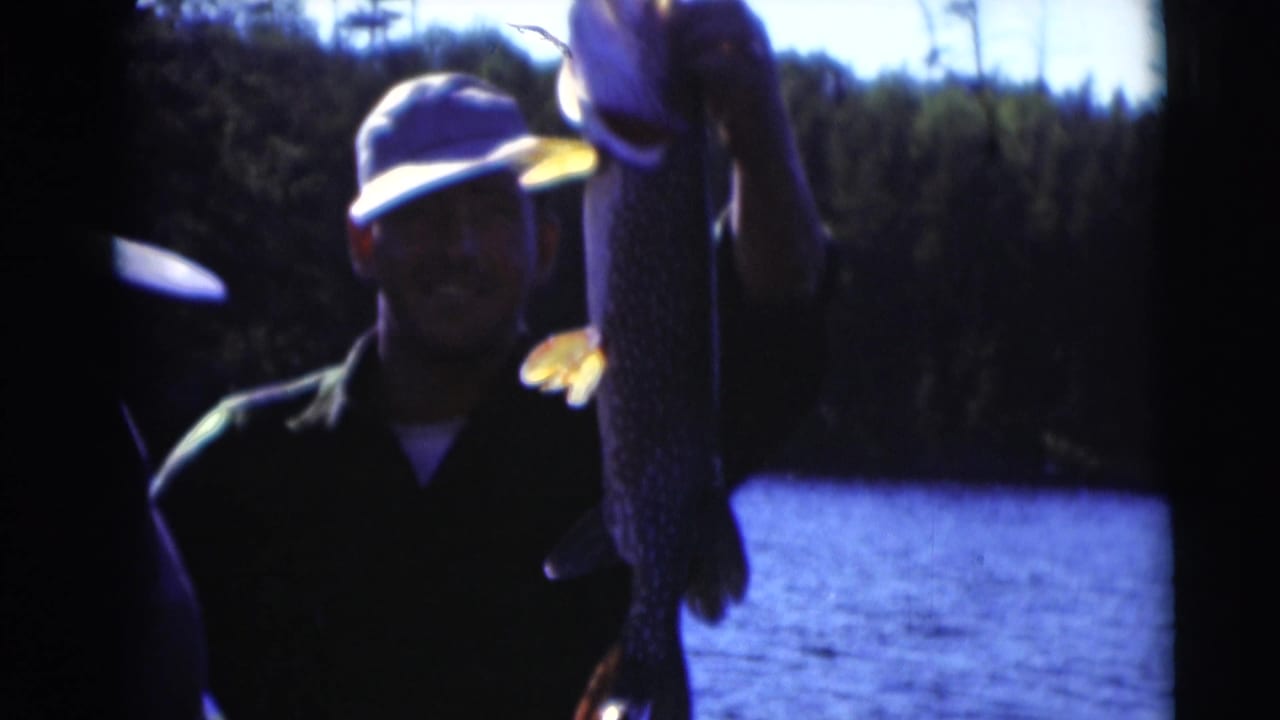 In supplied 1953 Baraboo, Wisconsin footage, a man in a cap holds up a large fish near blue lake water and trees.