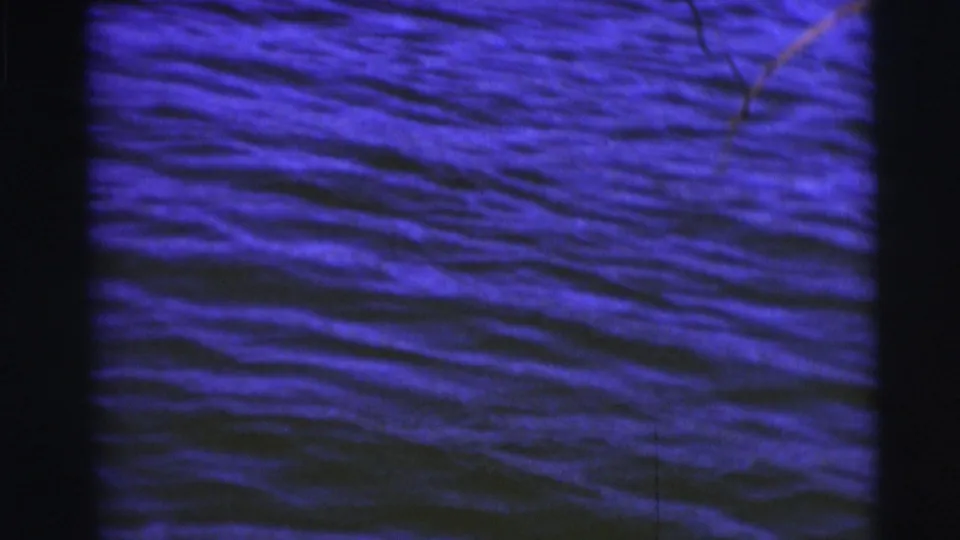 Close view of rippling lake water, with fishing lines entering near the top edge and dark film borders around the frame.