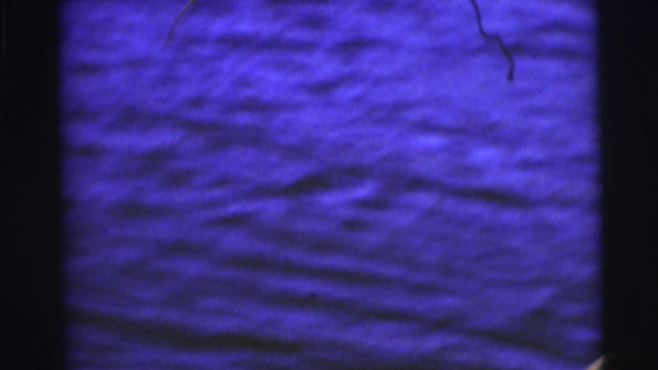 Close view of rippling lake water in blue-tinted 1953 8mm footage from Baraboo, Wisconsin.