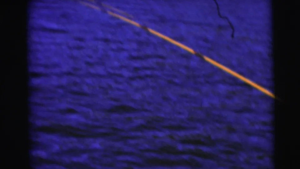 Fishing line or rod tip cuts across blue-tinted lake water in the Baraboo fishing home movie.
