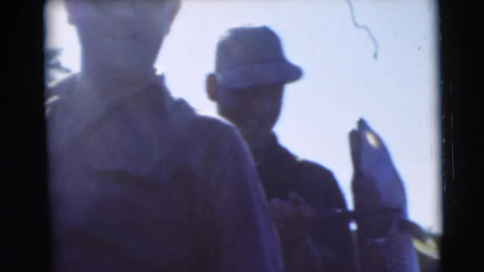 Two adults are partly silhouetted in the Baraboo fishing scene as the large pike is held up close to the camera.