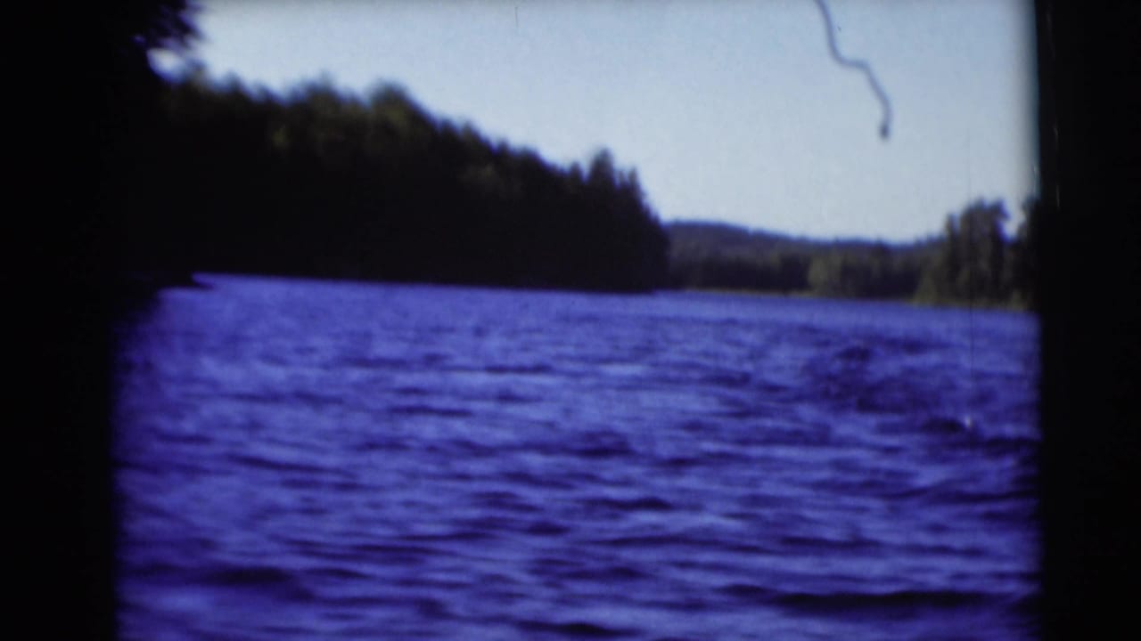 Wide 8mm view of rippling lake water near Baraboo, Wisconsin, with wooded shoreline and low hills in the distance.