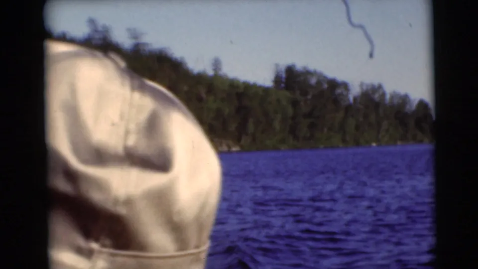 1953 Baraboo, Wisconsin lake view with a white hat or clothed shoulder in the foreground and trees across the water.