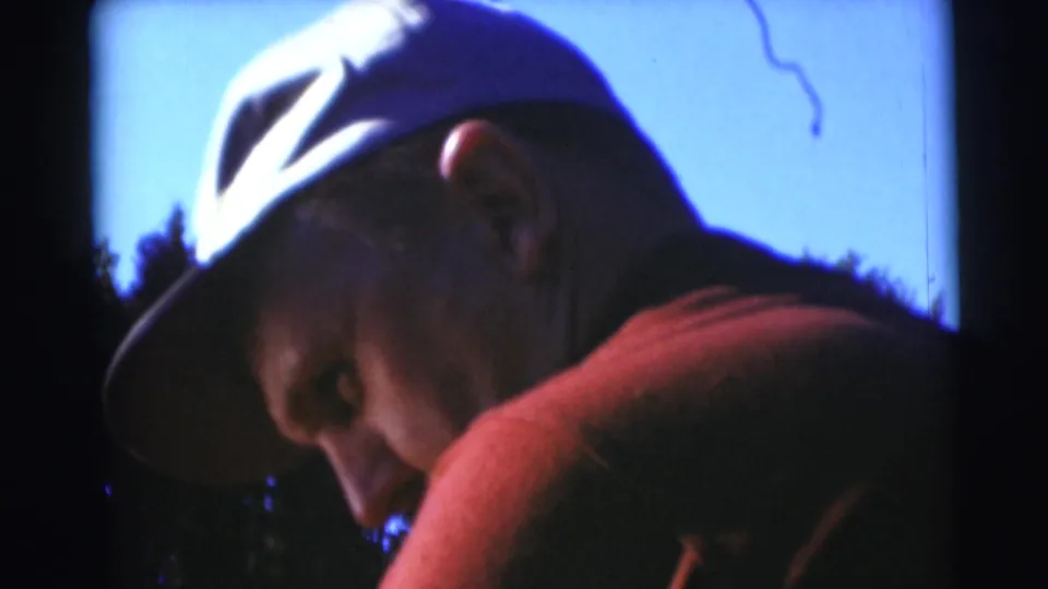 1953 Baraboo home-movie close-up of an adult man in a light baseball cap and red shirt, seen in profile near the lake.