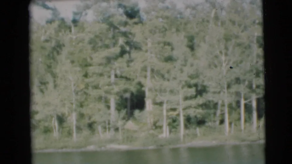 A wooded shoreline across calm lake water appears in the Baraboo, Wisconsin home-movie landscape shot.