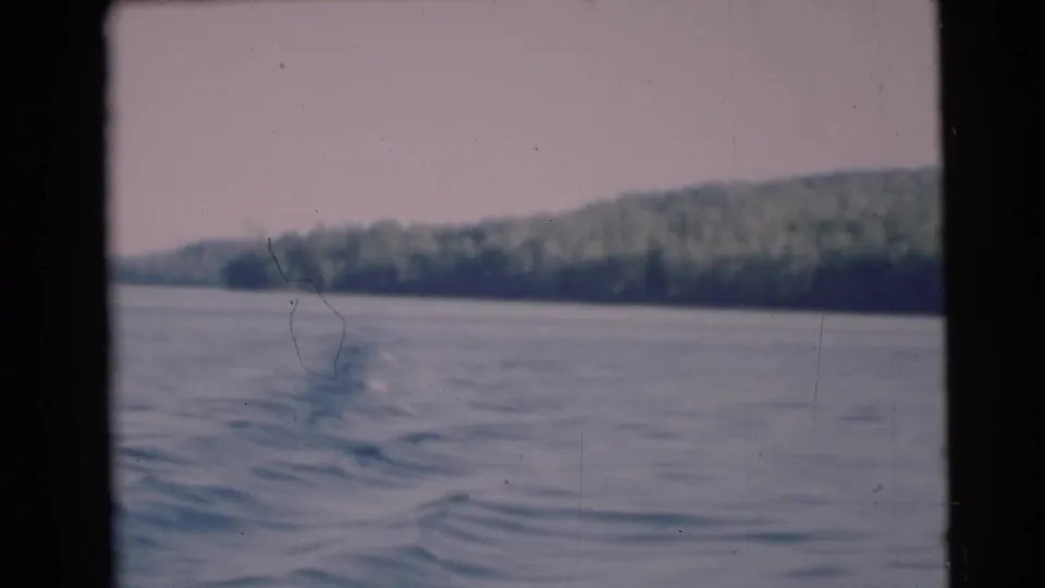 A 1953 8mm boat passenger view near Baraboo, Wisconsin, showing a broad river and tree-covered bank with visible film wear.