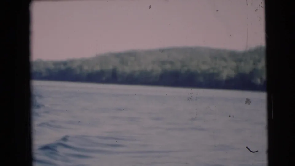 Final 1953 8mm frame from the Baraboo, Wisconsin boat view, with rippling river water and a soft tree-lined bank.