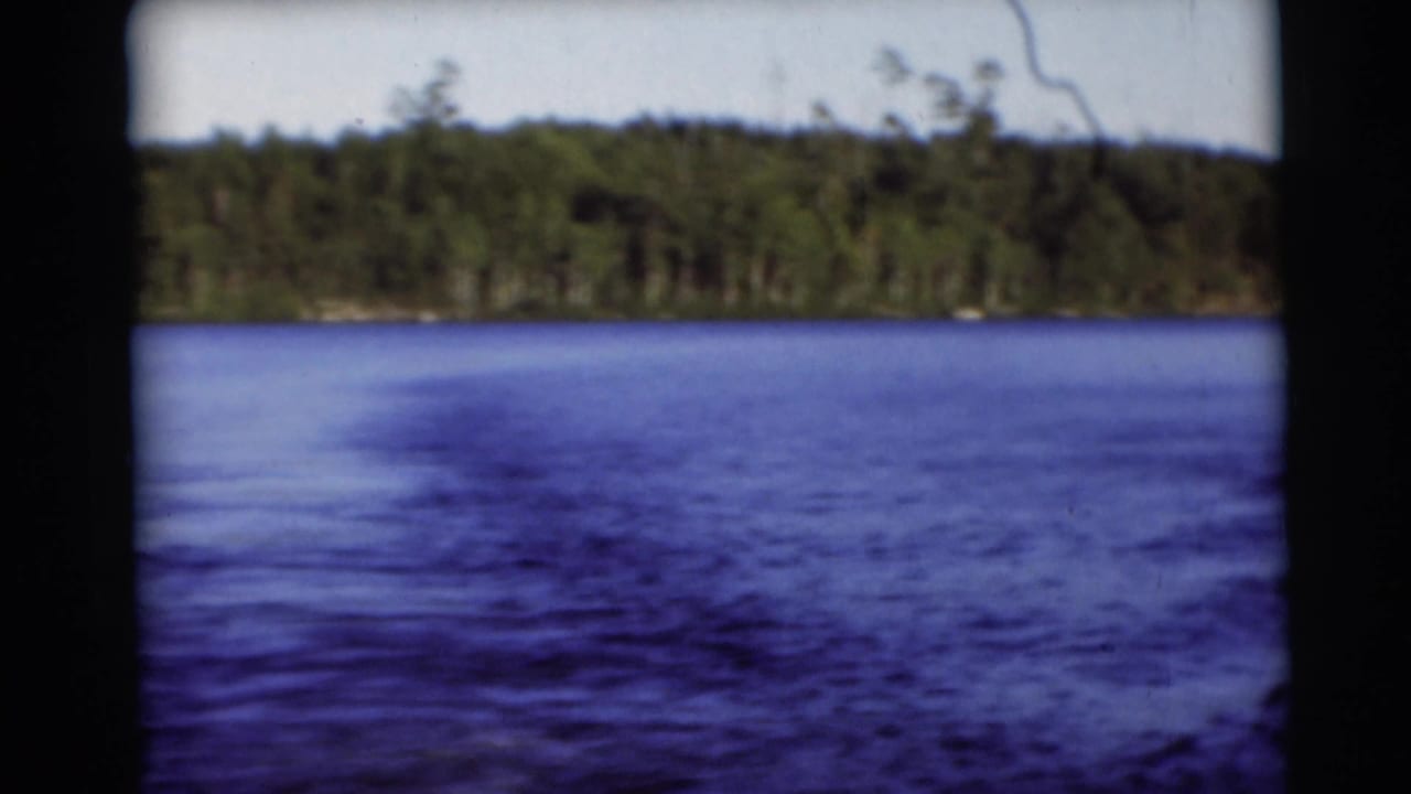 1953 Baraboo, Wisconsin 8mm frame showing rippled blue lake water and a distant forested shoreline from a boat.