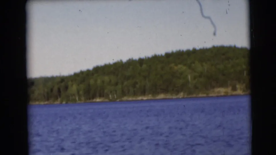1953 Baraboo, Wisconsin 8mm frame showing blue lake water and a distant wooded shoreline under pale sky.