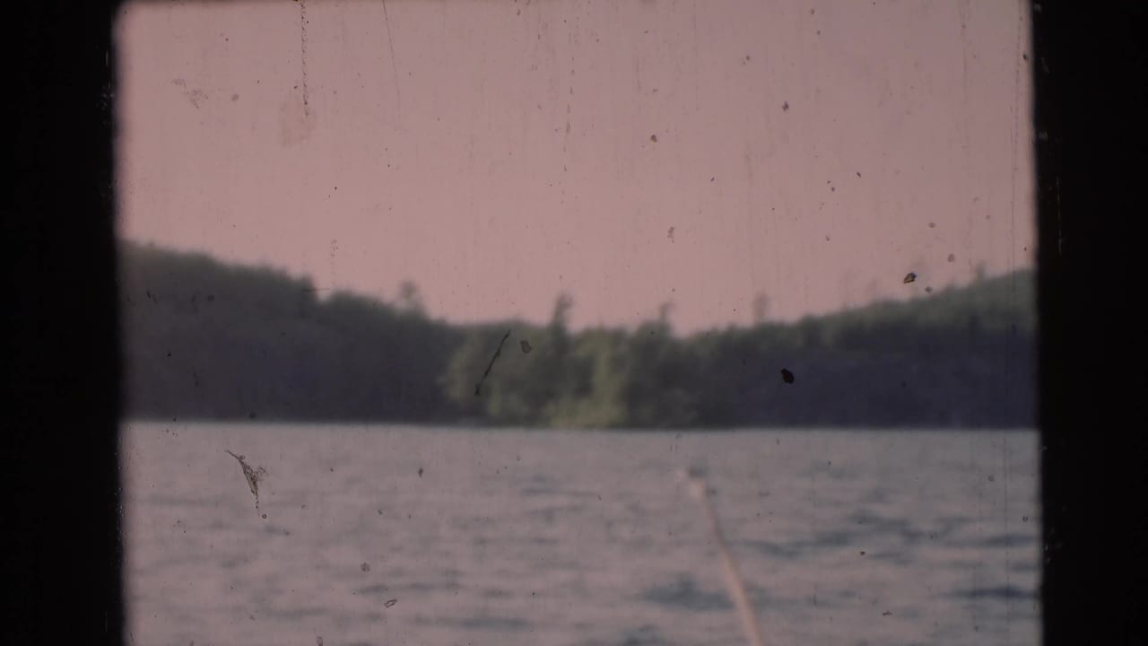 Lake surface with distant treeline, hills, and dark vertical boat framing.