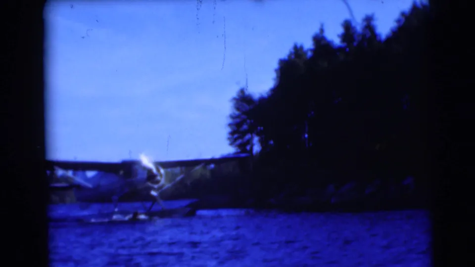 A small floatplane appears on lake water near a wooded shoreline in Baraboo, Wisconsin, according to the clip metadata.