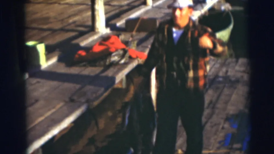 The man walks away along the dock in the 1953 Baraboo footage, with the red jacket and dock structures behind him.