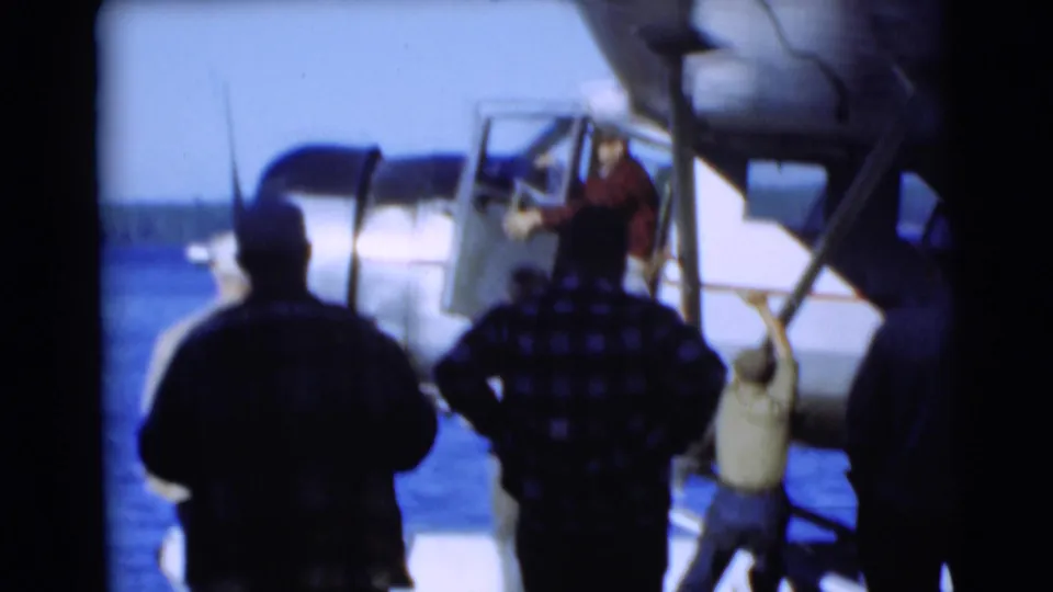 A man climbs into a white seaplane in Baraboo as several men observe from the lakeside dock.