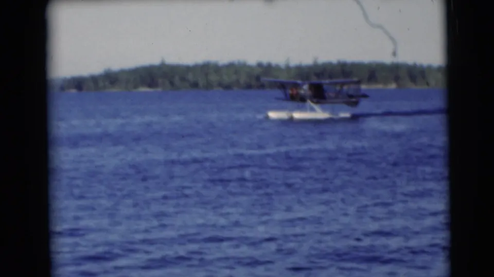 A pontoon seaplane moves across a Baraboo-area lake in 1953, with a low wooded shore in the background.