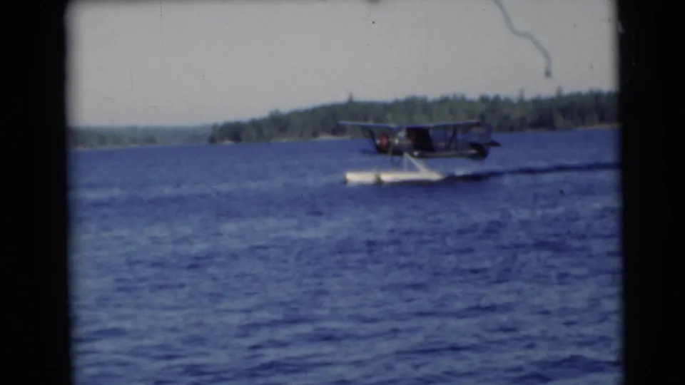 A 1953 Baraboo-area lake view shows the seaplane still moving across rippled water under a bright sky.
