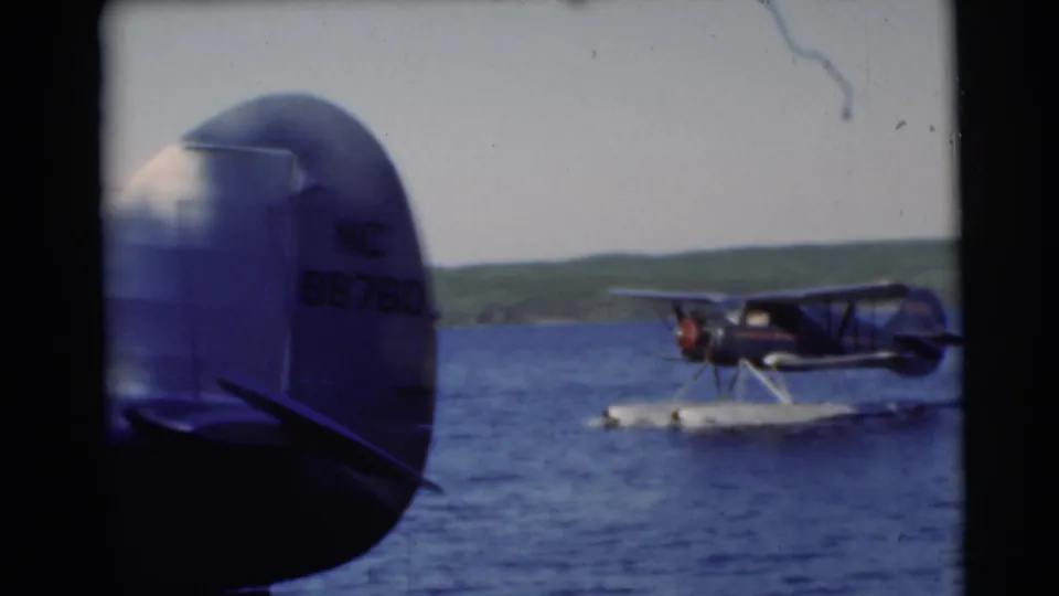 Foreground tail markings including NC 88760 are visible as the floatplane continues across the Wisconsin lake.