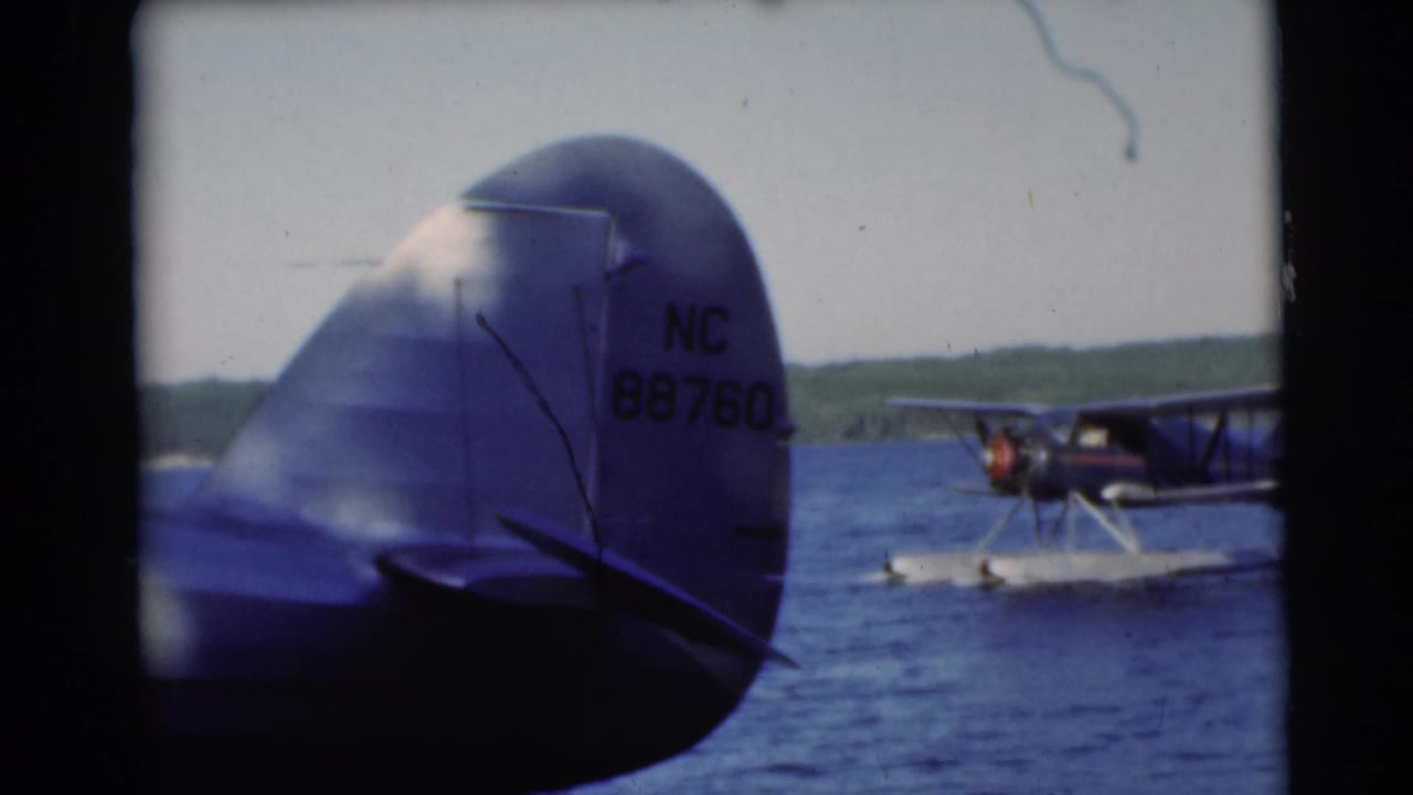 Aircraft tail marked NC 88760 beside a lake with a floatplane in the background.