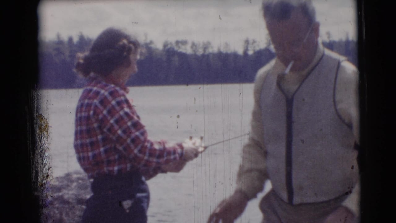 Adult woman and man standing by a lake with a fishing rod in bright daylight.
