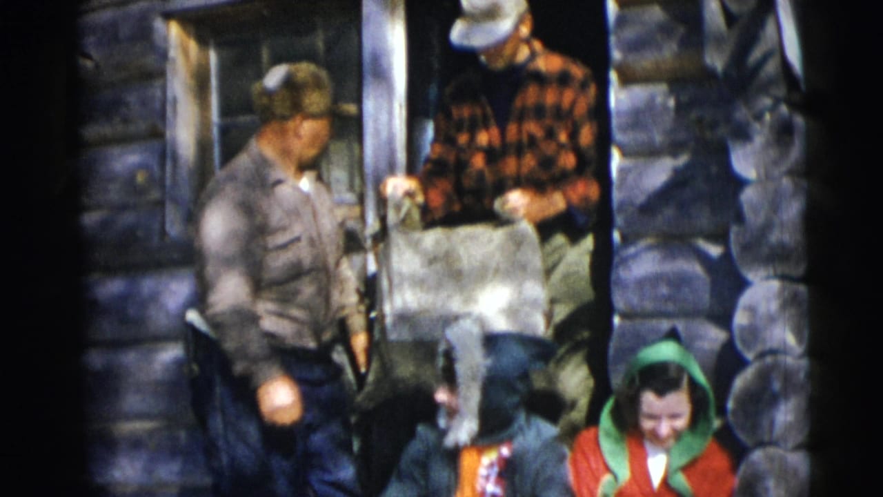 Adults at a Baraboo log cabin doorway handle a large light-colored bag as a seated woman in red appears at lower right.