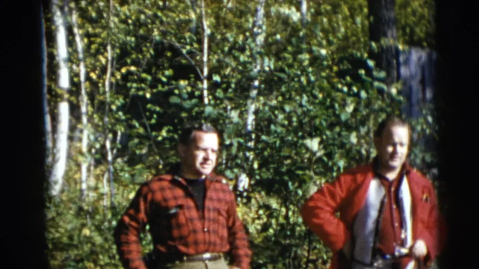 The final frame shows two adult men in red clothing in a 1953 Baraboo, Wisconsin wooded scene, partly framed by dark 8mm film edges.